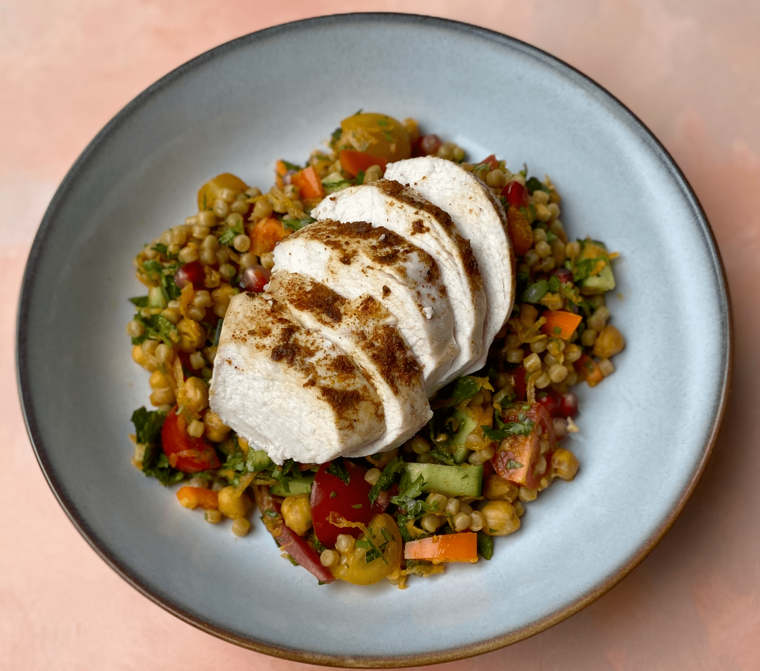 Spiced Chicken Couscous Bowls - A vibrant, high-protein bowl layered with ras-el-hanout chicken, crispy cumin roasted chickpeas, herby pearl couscous and fresh vegetables. The mix of lean chicken, legumes and whole grains keeps the dish rich in protein (≈ 55 g per serve) and fibre for long-lasting energy.